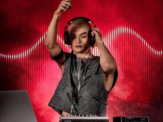 Artista utilizando la caja de ritmos Donner Essential D1 con auriculares, destacando sus 12 canales, 8 efectos por canal y 3 efectos globales.