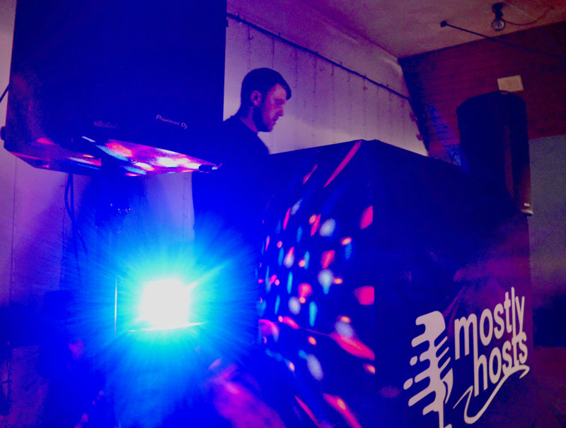 DJ actuando bajo luces LED en el Crosville Social Club, con altavoces Pioneer DJ XPRS2 de 15" iluminados en primer plano.