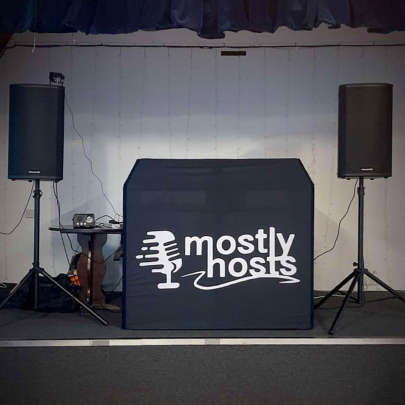 Cabina de DJ personalizada con el logo Mostly Hosts y dos altavoces Pioneer DJ XPRS2 en el escenario del club.