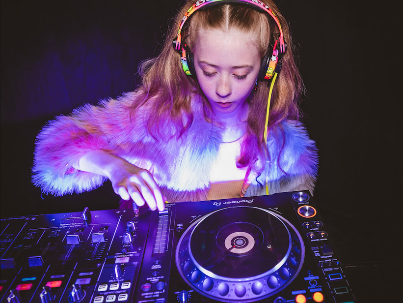 Niña mezclando música con una consola Pioneer DJ en un taller de AlphaTheta

