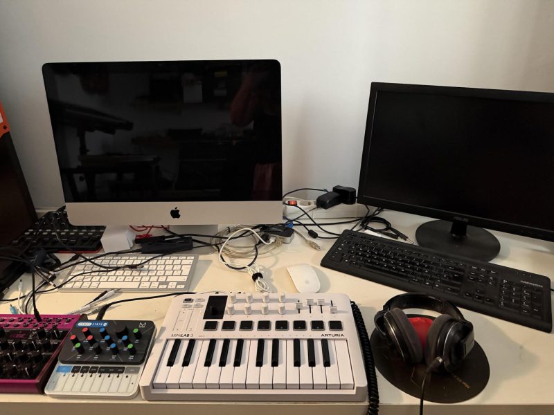Controlador MIDI Arturia MiniLab 3 en un estudio casero junto a iMac, auriculares y otros dispositivos de producción musical